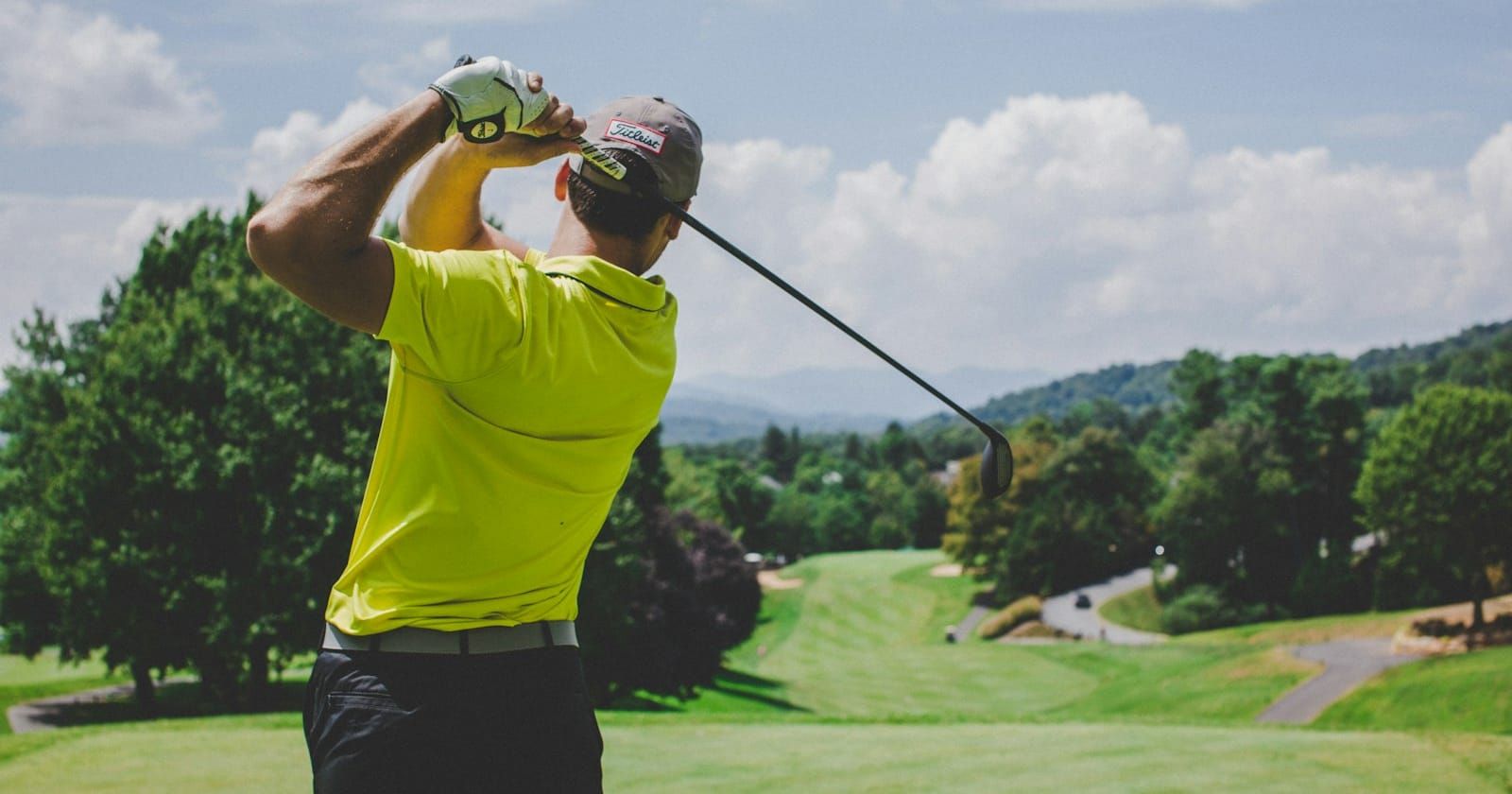 Golfer teeing off on a hillside golf course