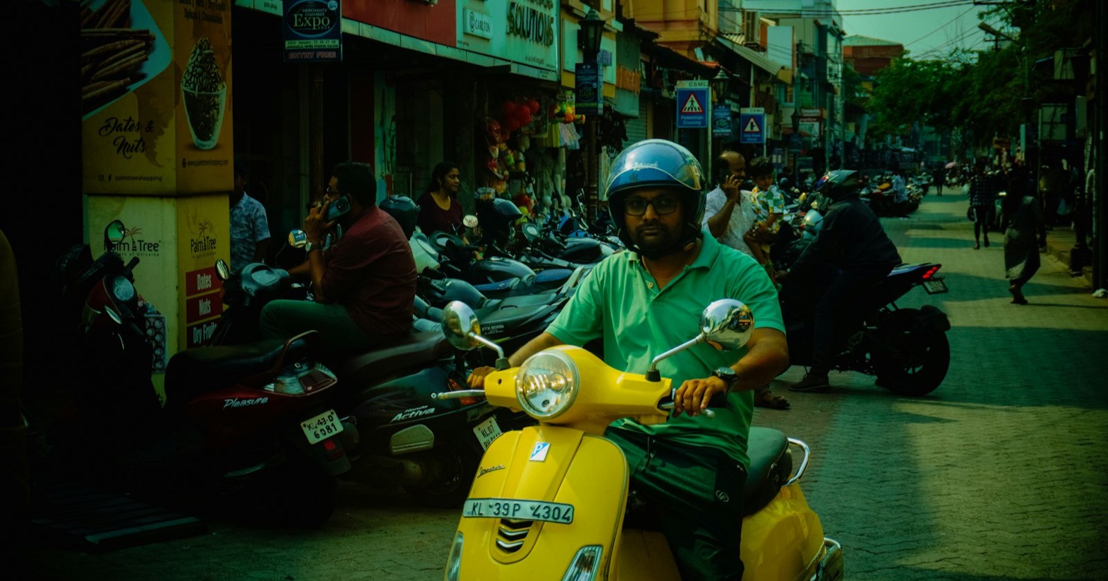 Rider in a helmet on a yellow Vespa in busy city street traffic